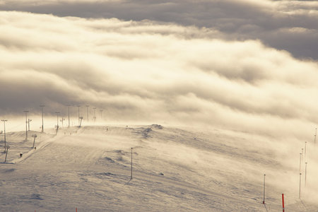 Stunning views of the ski slope and ski lift on the mountain in the middle of the clouds below and in front, sunset.の写真素材