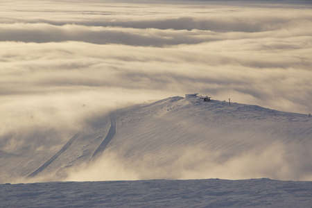 Stunning view of the ski station on the mountain in the middle of the clouds below.