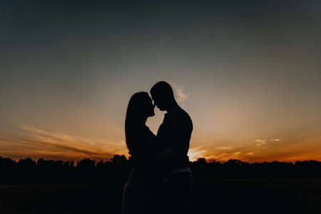 A couple in love on the background of a beautiful sunset creates an image of a heartの写真素材