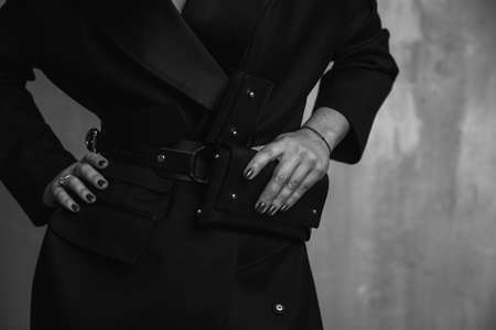 A business woman in a strict black coat and with a clutch in her hands goes out into the cityの写真素材