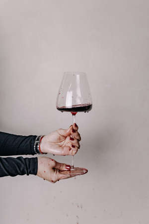 Drops of red wine flow down the glass in the hands of the sommelierの写真素材