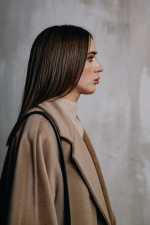 Profile of a girl in a coat against a gray wallの写真素材