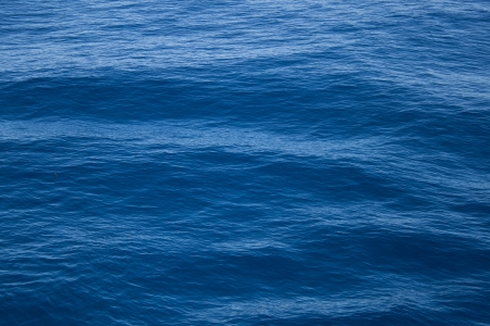 Background blue waves of the sea with sea foamの写真素材