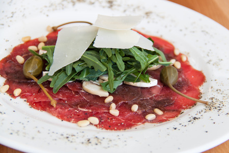 Carpaccio of beef with cheese on a white plateの写真素材