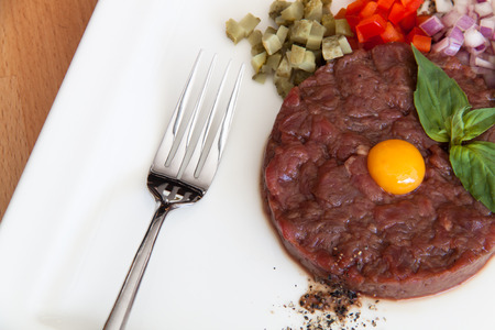 Tartar meat on a wooden table with a slice of white breadの写真素材