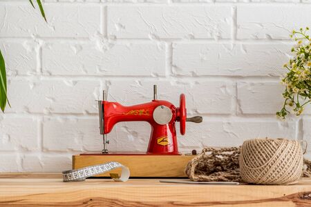 Red sewing machine on a wooden table. Sewing industry. Diy