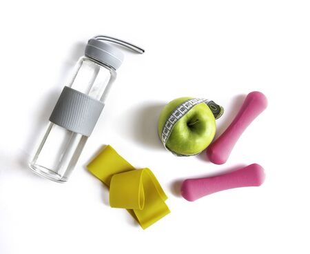 Apple with measuring tape, fitness elastic band, water bottle and dumbbellsの写真素材