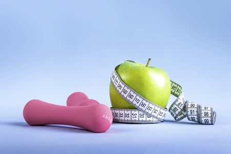 Apple with measuring tape and dumbbells on isolated backgroundの写真素材
