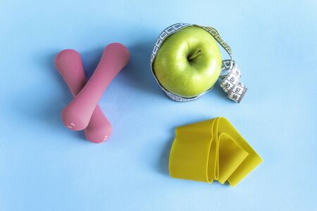 Apple with measuring tape, fitness elastic band and dumbbellsの写真素材