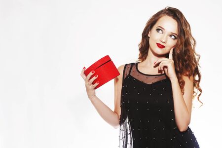 Beautiful girl with a gift, a red box looks away thoughtfully. The girl thinks what to present for...