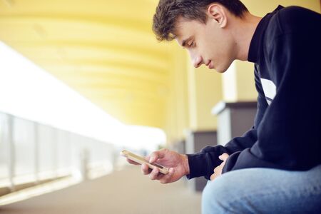 Man using mobile application on his smartphone at train station, travel. Handsome in railway...
