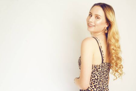 Portrait of a beautiful blonde with long hair. Girl with gold earrings, costume jewelry, dress with leopard print. Young girl with braces, plate, perfect teeth. Fashion girl in leopard with braces. Copy spaceの写真素材