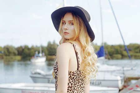 Girl on background of yachts, sailing boats smiling, looking at the camera. beautiful blonde is...
