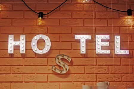 Plate hostel glowing lamp letters. The inscription hostel on a brick wall.の写真素材