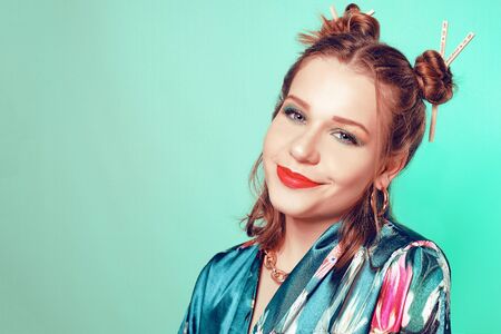 Japanese / Chinese / Asian style girl with chopsticks in her hair. Girl with an interesting hairstyle, on a green background in a Japanese, Chinese bathrobe. The girl is looking at the camera. Sushi discountsの写真素材