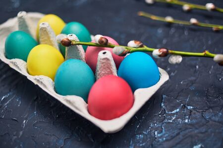 Happy Easter. Painted multi-colored, pastel eggs in an egg carton. Flowering pussy-willow cats, spring flowers on an abstract background of dark color. The beauty of Easter.の写真素材