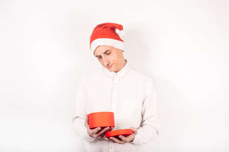 New Year's photo. A man in a santa hat on a white background holds a box in his hands, the guy looks...