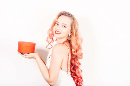 New Year's photo. A girl with pink hair in a beautiful dress holds a box with a gift in her hands