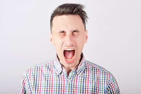 Guy student shouts loudly on white backgroundの写真素材