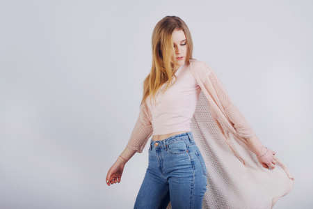 A girl in a pink sweater stands on a white background. Blonde student smilingの写真素材