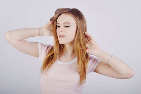 The blonde with gorgeous hair, the girl touches her hair with her hands, care.の写真素材