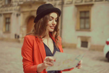 Happy woman on vacation with map, traveler walks the city. Sunny day. Back view. A young tourist...