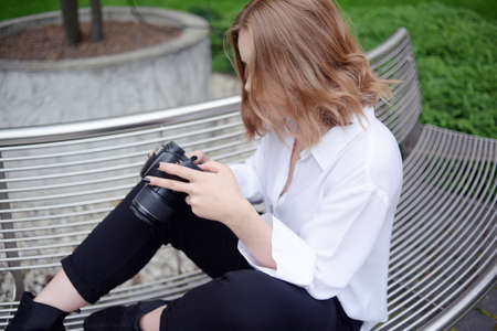 Girl photographer is trying to figure out the settings of the camera, model looks at screen of a SLR...