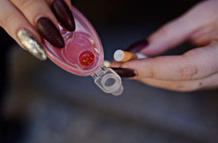 The girl's hands hold capsules for cigarettes and puts them into cigarettes. Banning flavored...