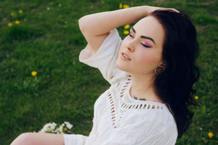 The girl lies on the grass in the park. Beautiful pink makeup on a girl.