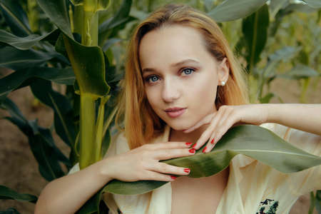 Portrait of a girl in the leaves of corn. Cute girl in nature. Natural cosmetics, beauty and youth