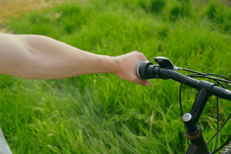Male hands on a background of grass, bike, mountain handlebar. Brakes