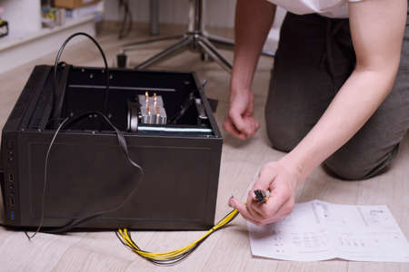 A man at home collects, disassembles a computer. Hands of a man hold wires, connects wires....