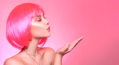 Girl with pink hair, brown hair. The model sends a kiss, a place for a product, for textの写真素材