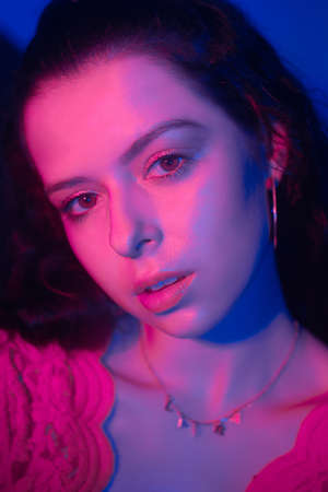 Photo of a woman in neon, beautiful photo in a teen club. Red-blue color. Woman portrait, eye makeup...