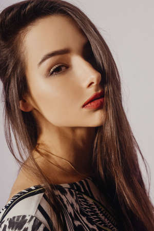 Portrait of a beautiful girl, brunette with gentle facial features looks at the camera. Long, evil hairの写真素材