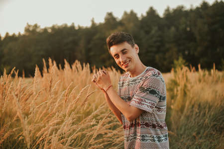 A gorgeous photo of a man walking in the forest against the background of a wheat field. A man on...