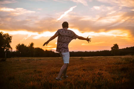 Man in the field at sunset enjoy life smiling, happy with victory, good news, screams, freedom.
