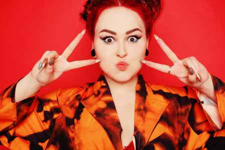 Beautiful girl on a red background. Red hair and tunnels in the ears, red dress and lips. Anime...