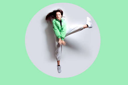A girl dances in a green jacket a beating light, a fashionable teenager moves, laughs, dances, a party. Brunette with long hair. Girl in flight, jumping.の写真素材