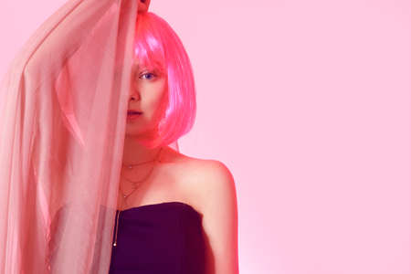 Girl with pink hair, brown hair. Model in a pink long dress, flying dress, fabric. Pink makeup,...