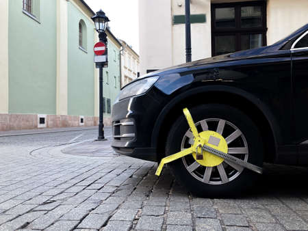 Car wheel blocked by wheel lock because illegal parking violation Wheel lock for anti-theft with the car on the road or concrete floor.の写真素材