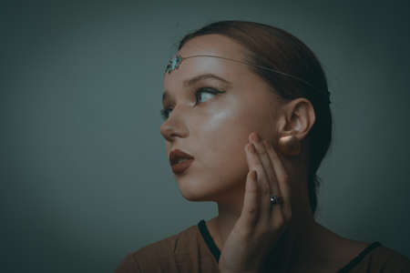 Girl with Dubai make-up. Perfect arrows, red lips, gold jewelry, jewelry on the forehead. Indian girl, indian jewelry.の写真素材