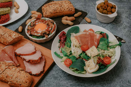 Festive table with meat, bread and snacks. Scrambled eggs with bacon, olives and vegan cutlets. Lunch or Dinner. Excellent breakfast. Salads and cheeses.の写真素材