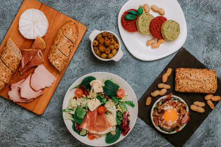 Festive table with meat, bread and snacks. Scrambled eggs with bacon, olives and vegan cutlets. Lunch or Dinner. Excellent breakfast. Salads and cheeses.の写真素材