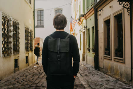 A man travels in Europe street walks through the streets of the old city, with a briefcase. Student travels alone. A young manの写真素材