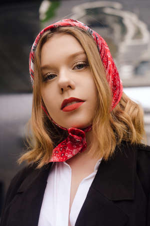 Portrait of an incredibly beautiful girl with blue eyes. Fashionable photo. Trendy style in clothes, a girl in a silk scarf and red lipstick and blue eyes. Short hair blondeの写真素材