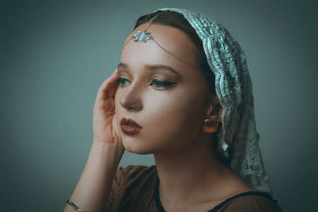 Girl with Dubai make-up. Perfect arrows, red lips, gold jewelry, jewelry on the forehead. Indian girl, indian jewelry.の写真素材