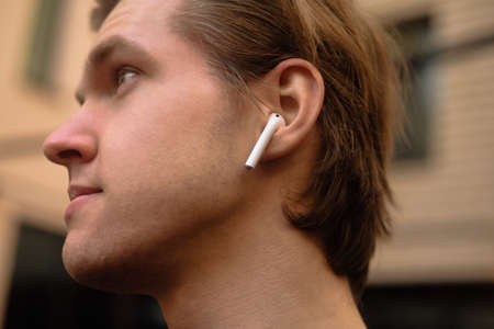 Man in wireless headphones outdoor, street, restaurant. Man listening to e-book, the guy is listening to music.の写真素材
