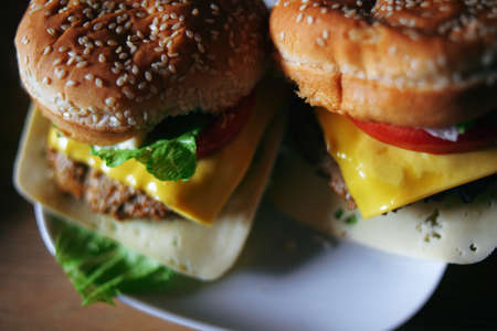 Photos of homemade burgers. Steak and white bun with sesame seeds, cheese and cabbage, tomatoes. Homemade food.の写真素材