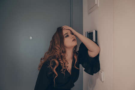 The girl came home after a hard day at work, she is falling off her feet, tired, exhausted. A woman after a party came home in the morning or late at nightの写真素材